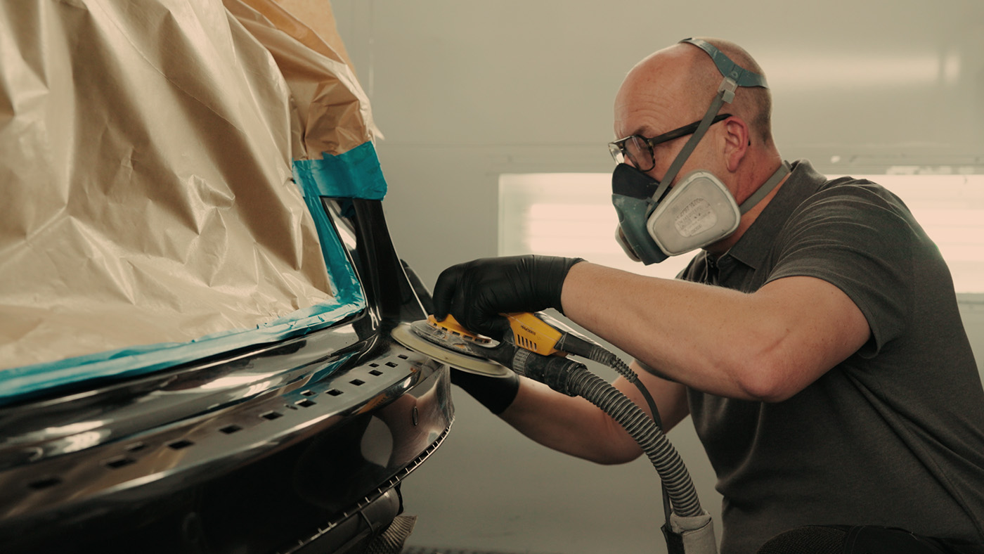 Slibning af lakskade på bilens kofanger som forberedelse til reparation