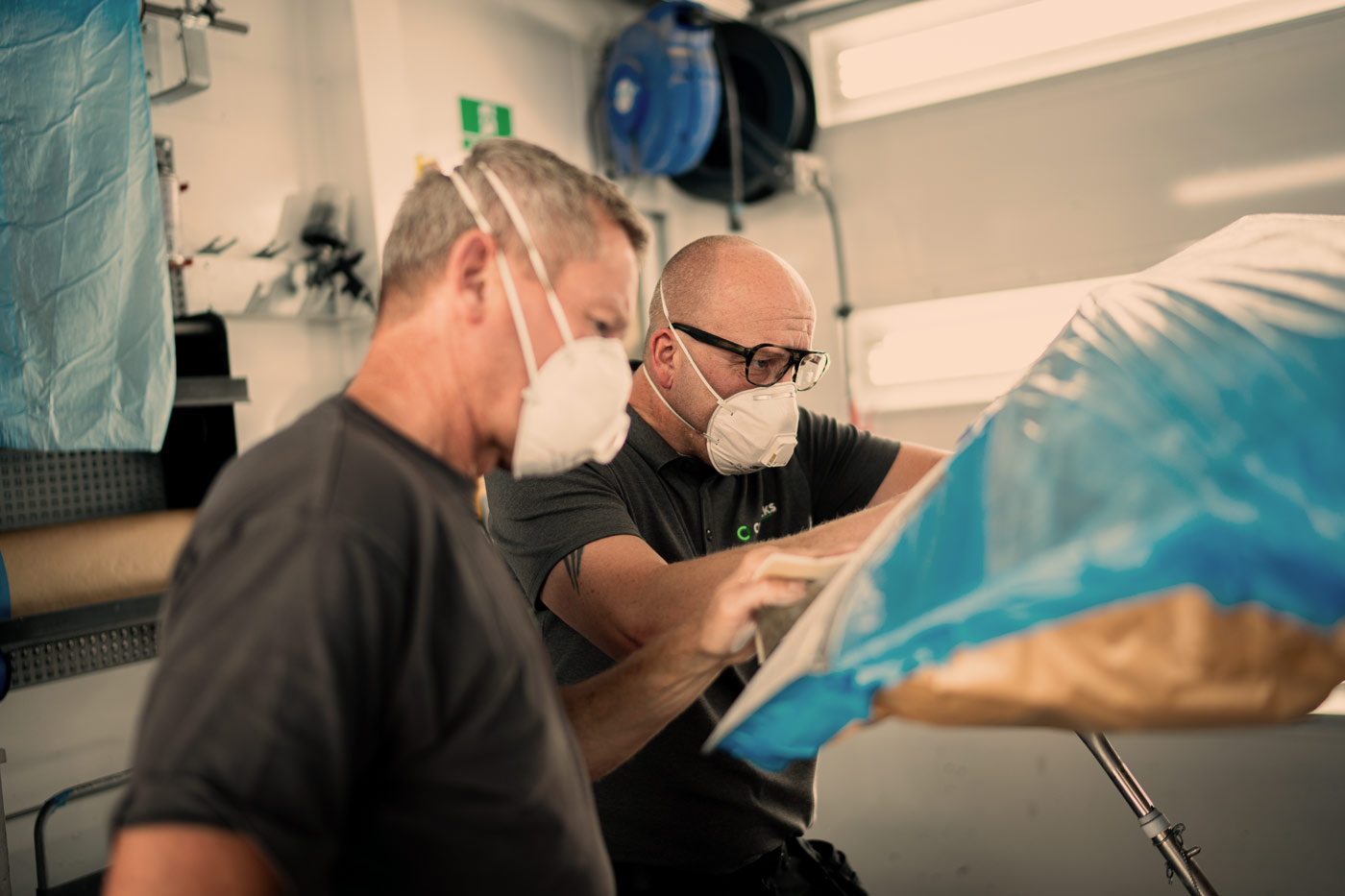 To teknikere arbejder sammen om effektiv bilreparation i værkstedsboks