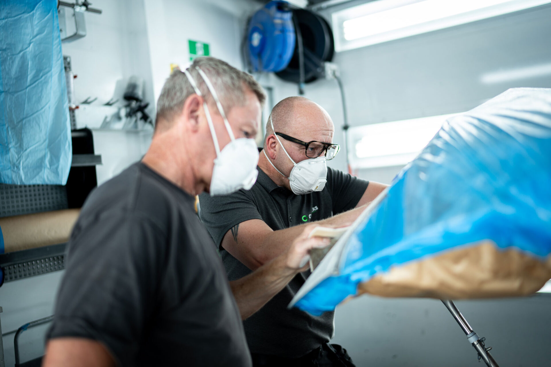 To teknikere arbejder sammen om effektiv bilreparation i værkstedsboks