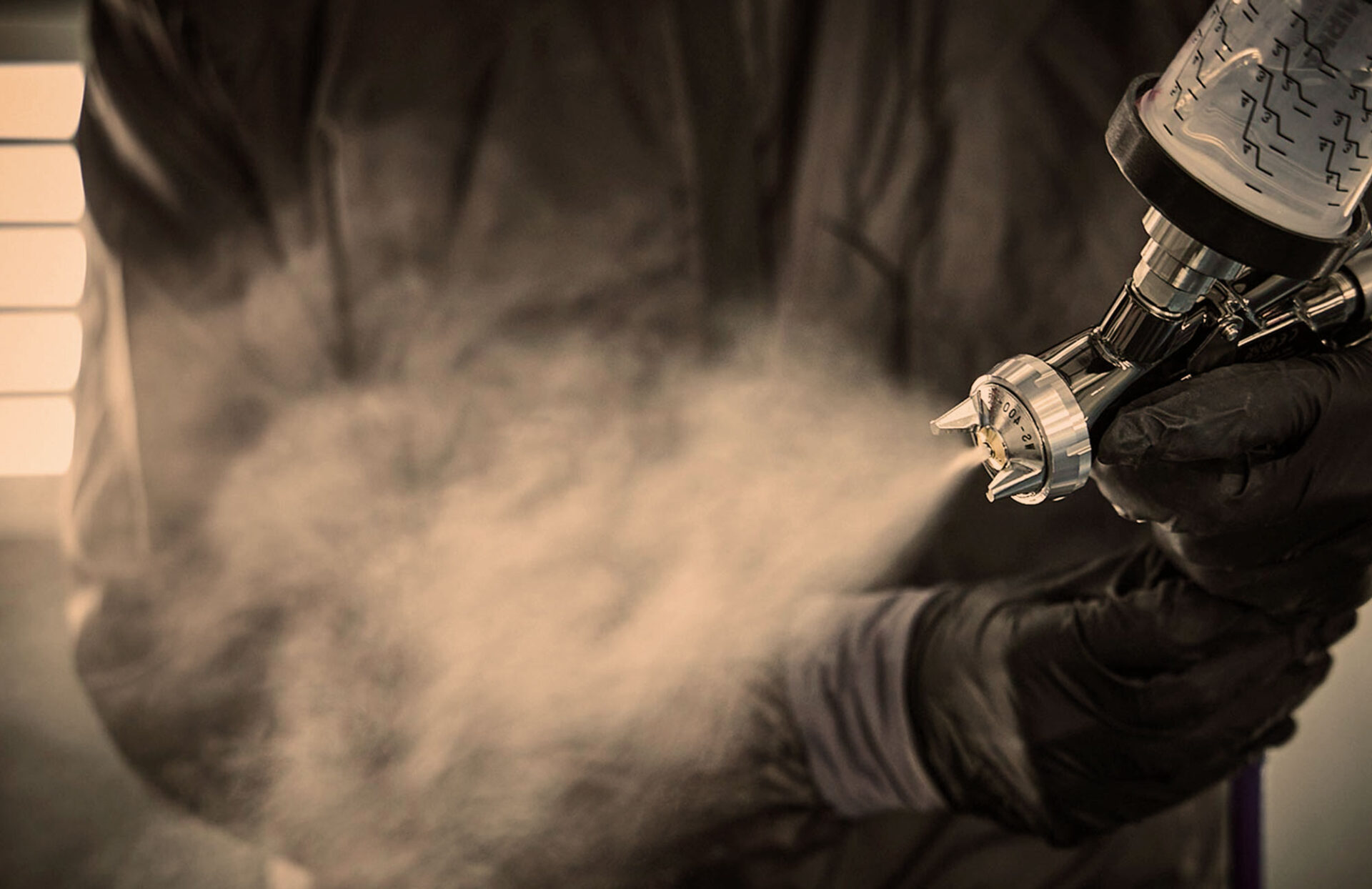 Lakering af bil med sprøjtepistol under reparation hos Carbucks