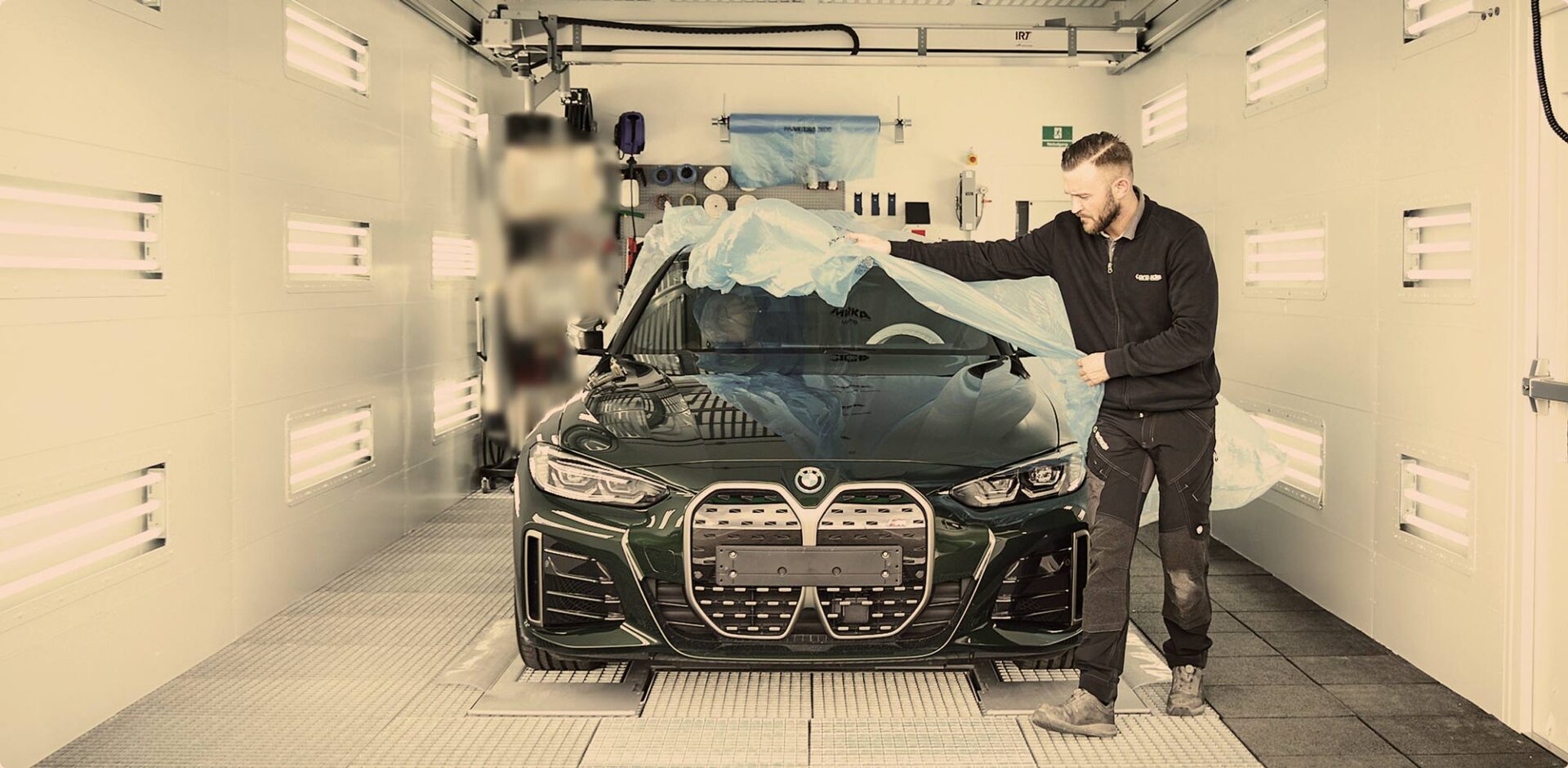 Tekniker fra Carbucks afdækker bil før lakreparation i værkstedsboks